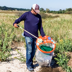 guy picking up trash at beach