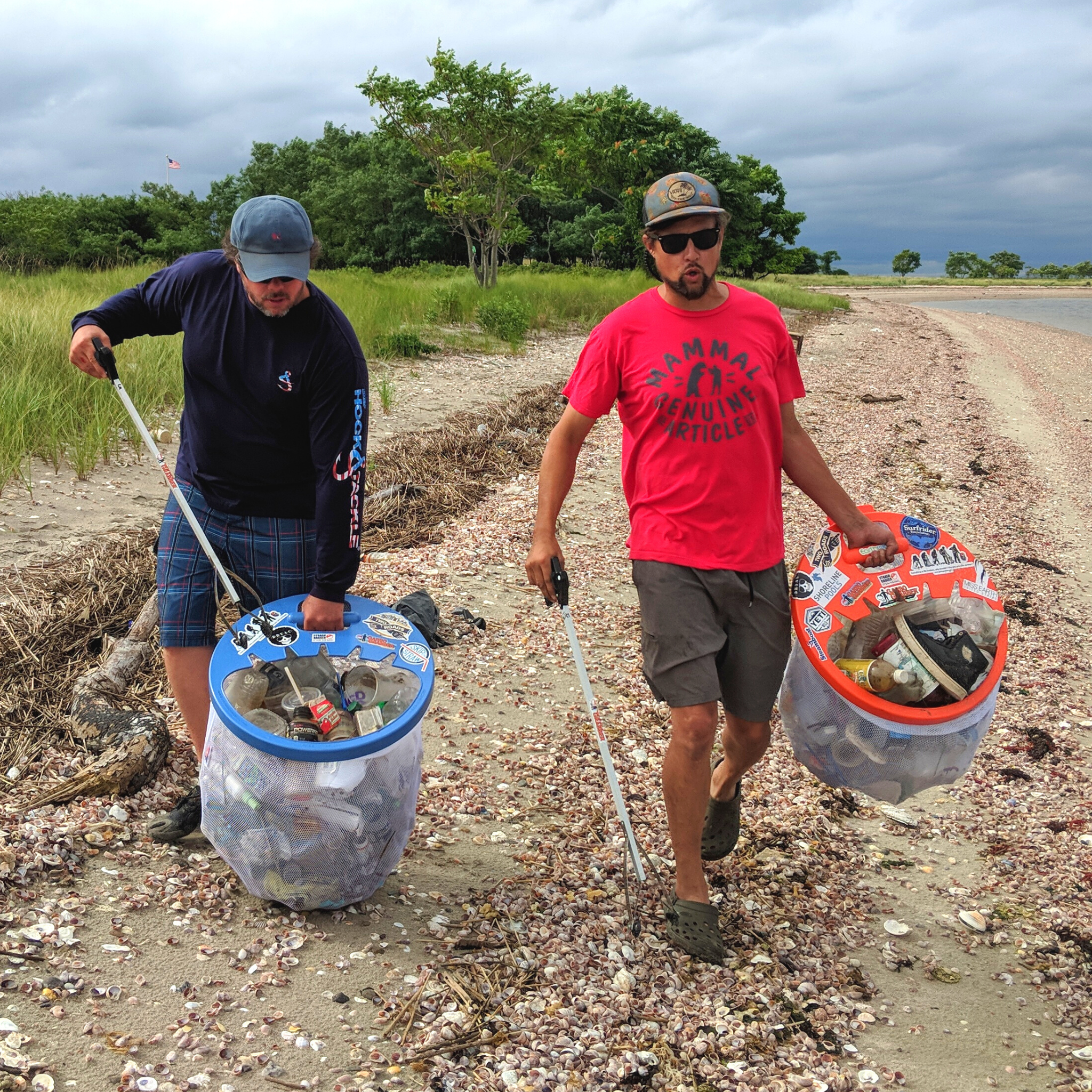 2 guys picking up trash at beach