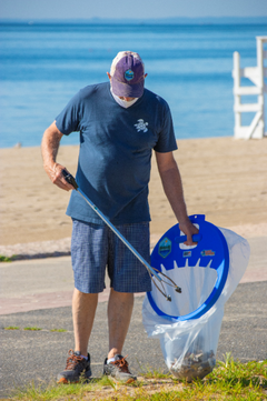 man picking up trash with a blue trash bagger